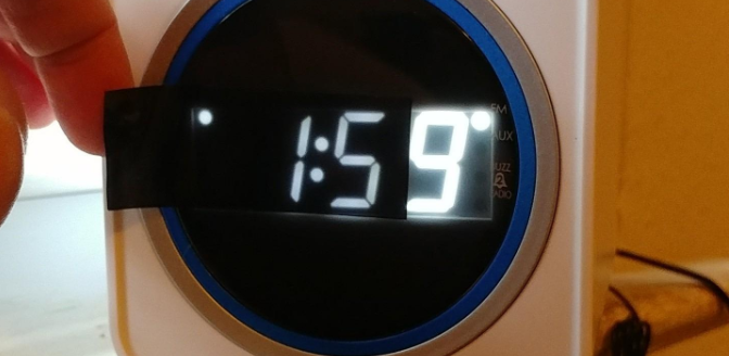 A clock with the light dimming sheet over it showing that it&#x27;s dimmer now