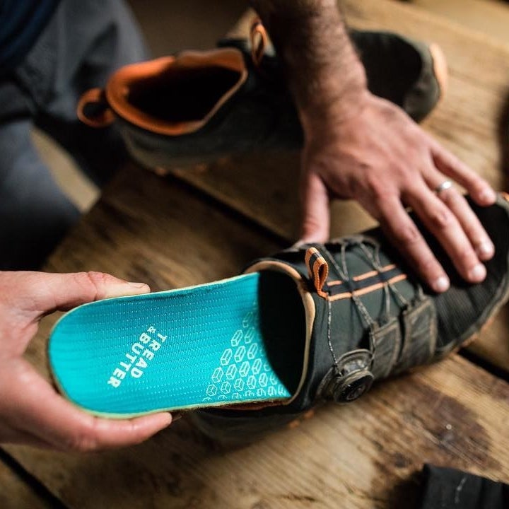 someone putting shoe inserts into a pair of hiking shoes