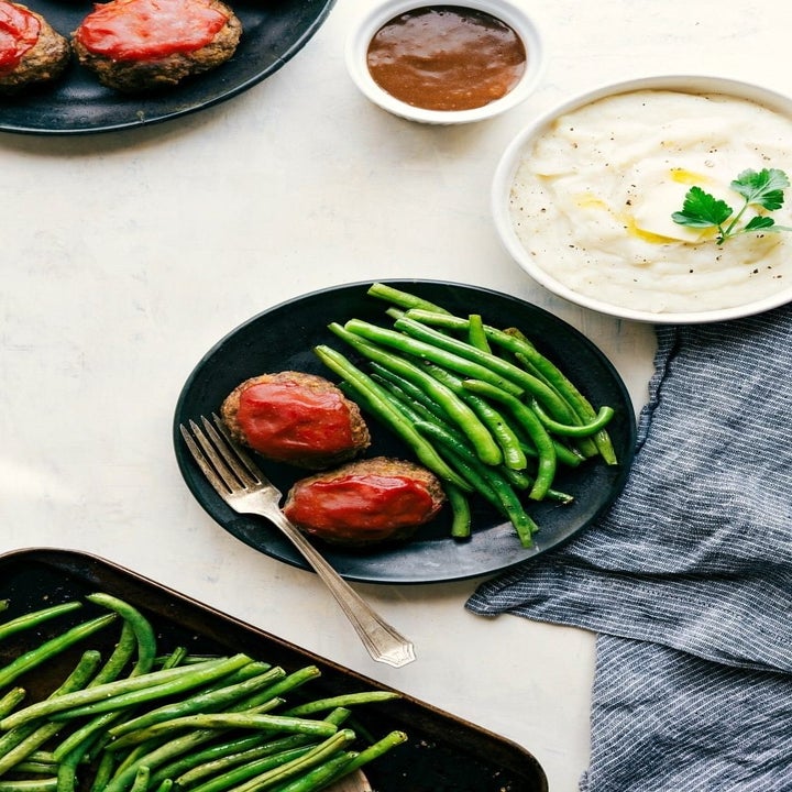 Plates of food featuring mini meatloafs with sauce, green beans, mashed potatoes with butter, and a fork