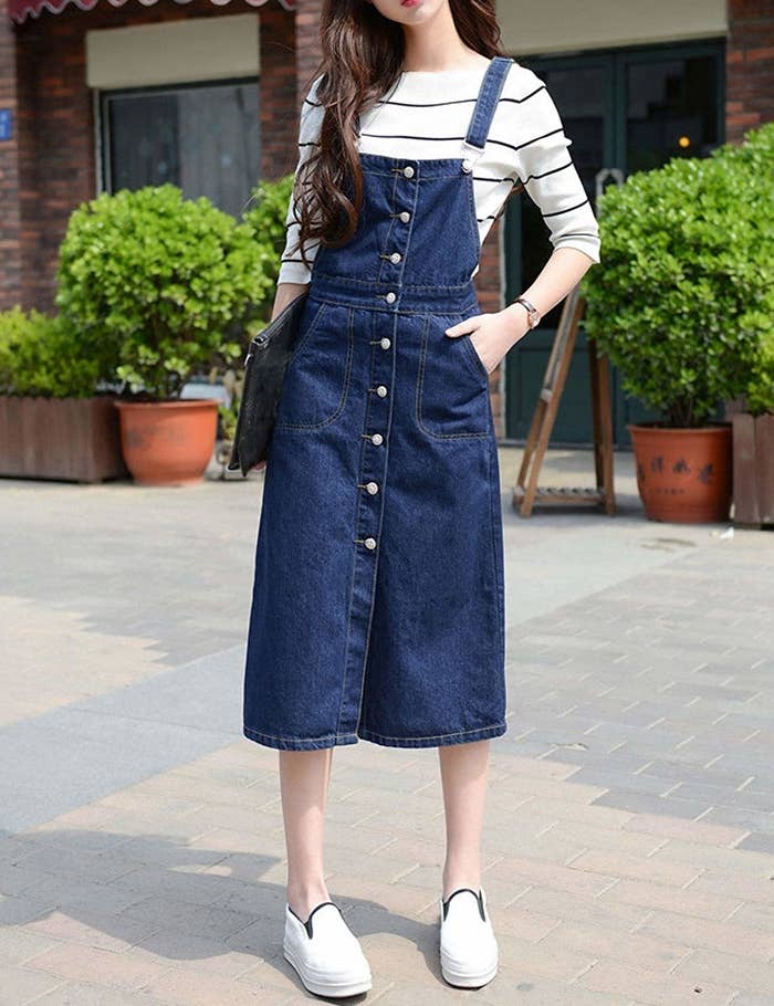 A model wearing the midi-length, button front dress in the dark wash with their hand in one of the side pockets