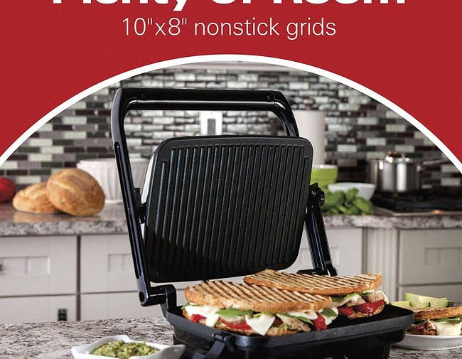 a panini press on a counter with two large sandwiches on it
