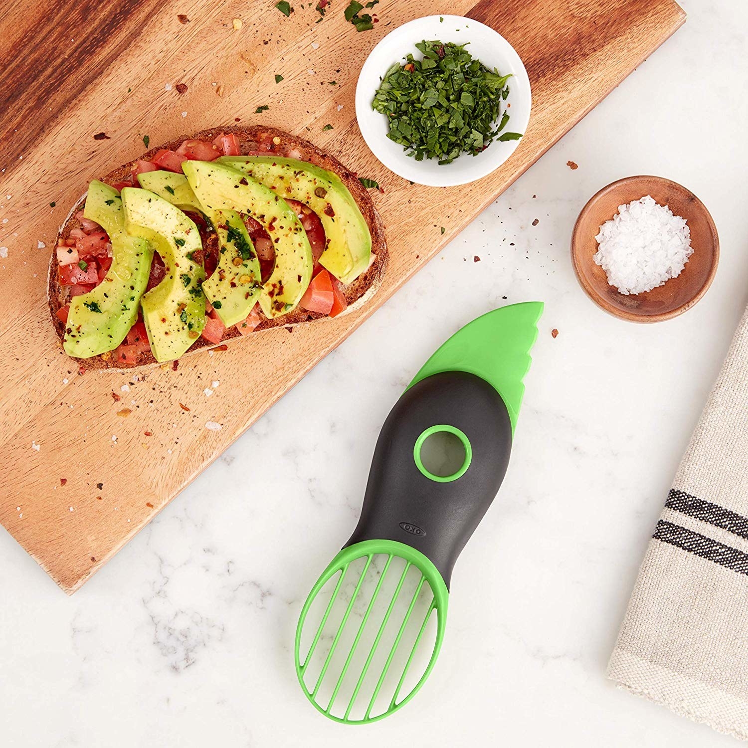The avocado tool with pitter, knife, and slicer built in next to some avocado toast