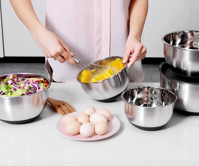 A model whisking eggs in one of the bowls, with other ingredients in the others
