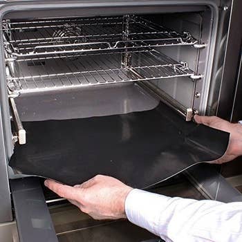 Hands placing the liner on the floor of an oven