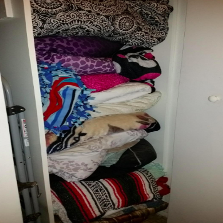 Reviewer's messy closet filled with blankets and towels 
