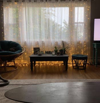 A living room window with the string lights and the sheer curtains