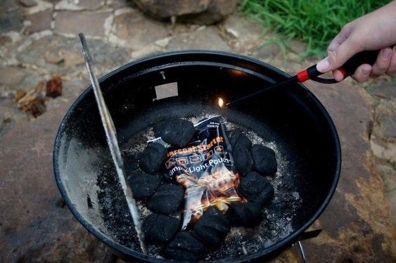 reviewer image of a hand lighting instafire on top of coals in a small grill