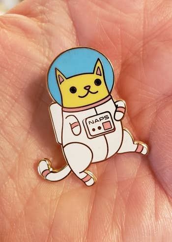 the tiny cat pin in an astronaut suit with the word 