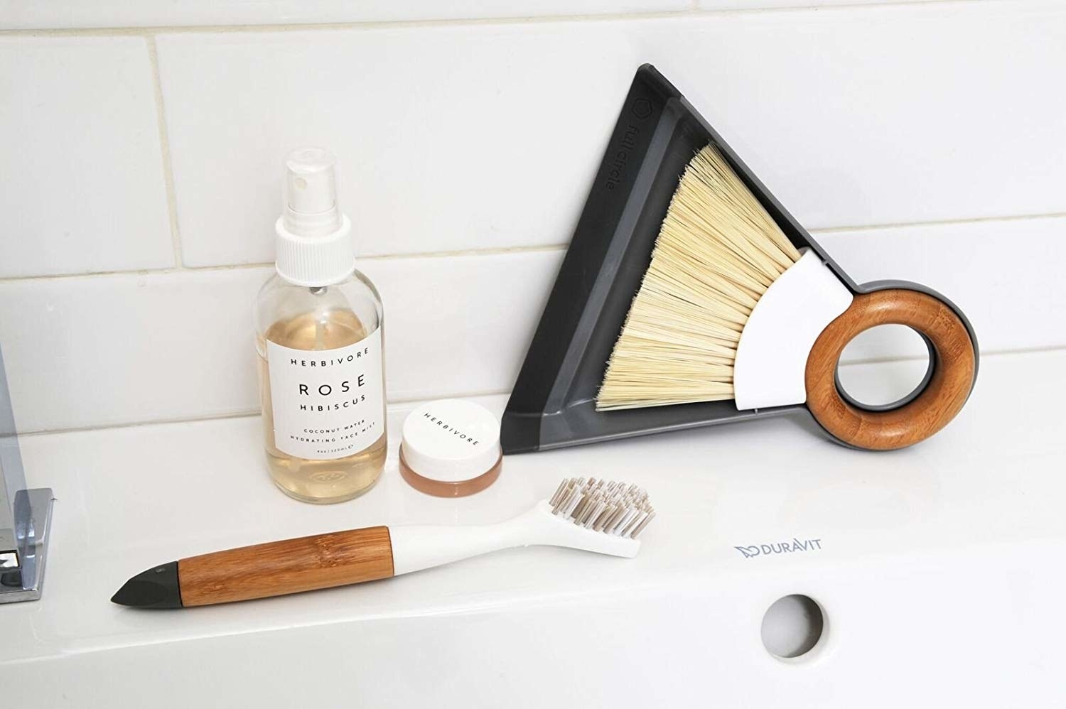 minimalist dustpan with a brush that fits inside it and a round wooden handle