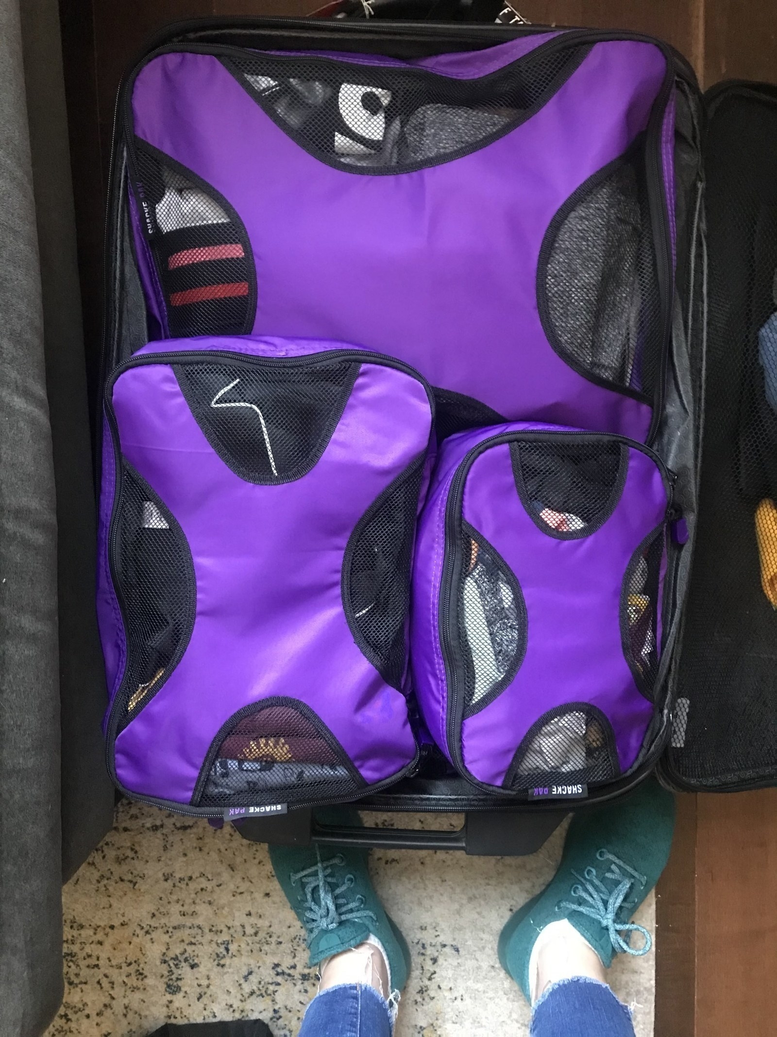 writer&#x27;s suitcase full of three purple mesh and fabric packing cubes
