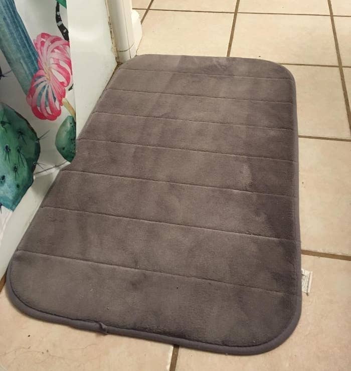 reviewer photo of the bath mat in gray in front of a shower