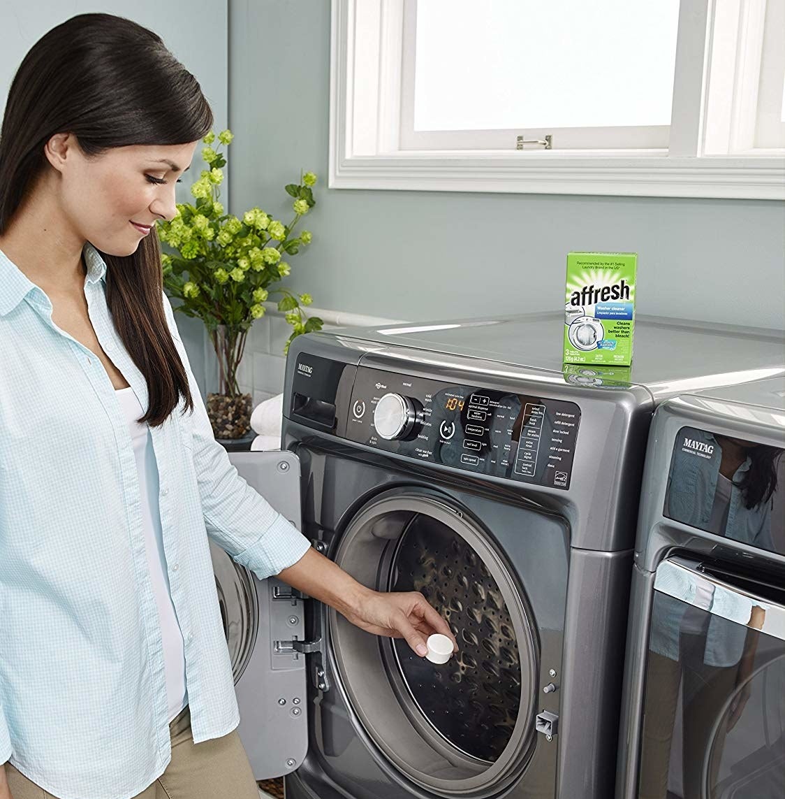 A person placing a small detergent pod into their washing machine