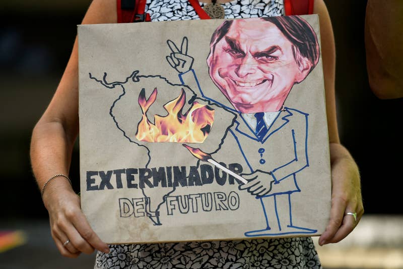 Luis Robayo / AFP / Getty Images An activist at the Brazilian consulate in Cali, Colombia, holds a sign reading, 'Exterminator of the Future' on Aug. 23.