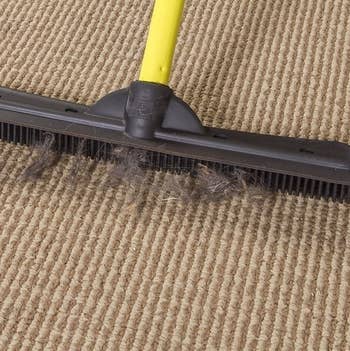 broom picking up hair from low-pile carpet