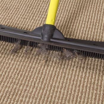 broom picking up hair from low-pile carpet