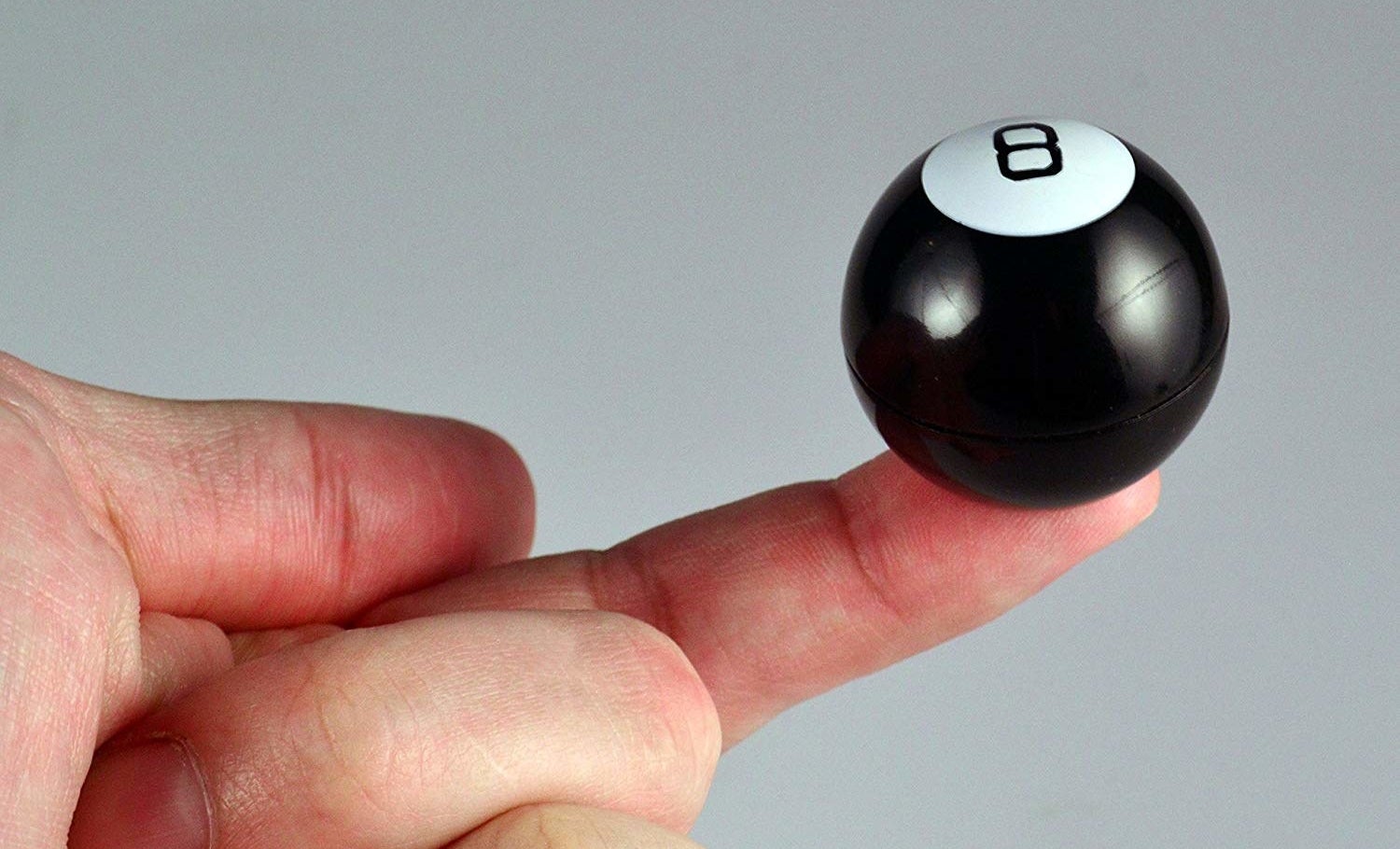 a model holding out a finger and balancing a mini magic eight ball