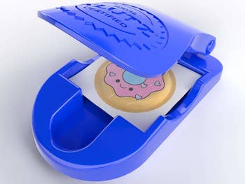 A small plastic blue press with a puffy doughnut sticker inside