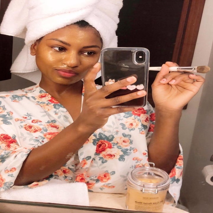 Reviewer with glowing skin while product is applied with brush 