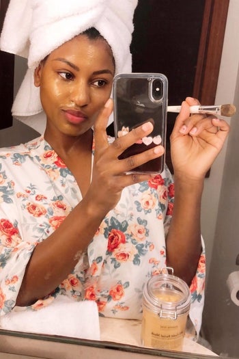 Reviewer with glowing skin while product is applied with brush 