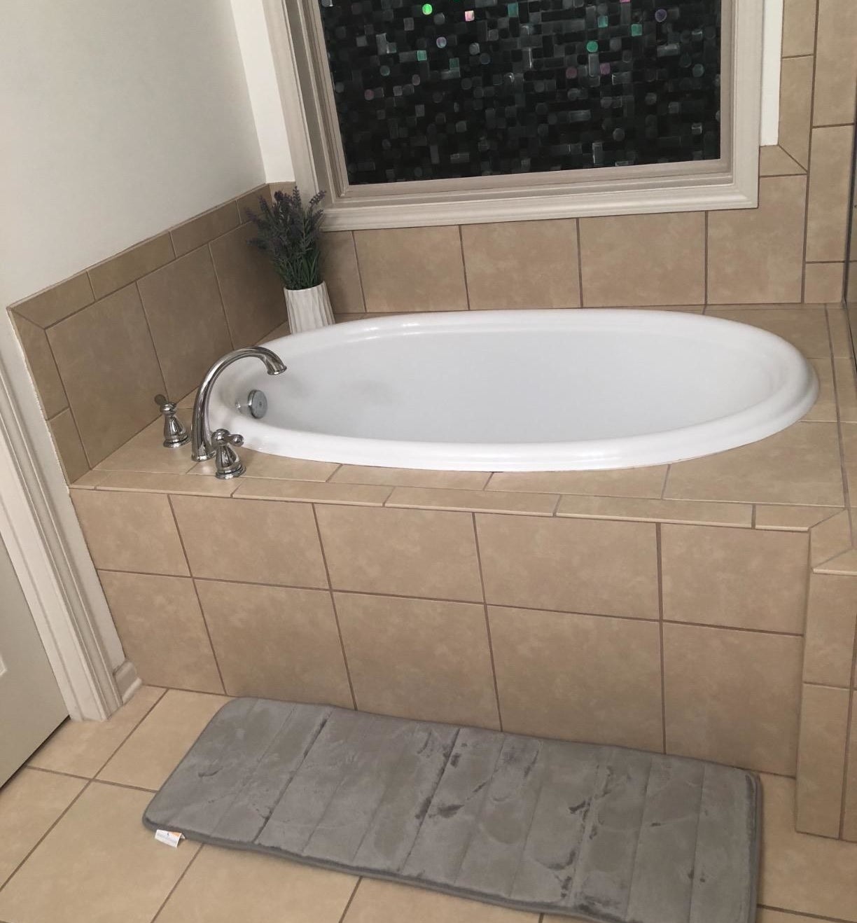 reviewer photo of the bath mat in gray in front of a bathtub