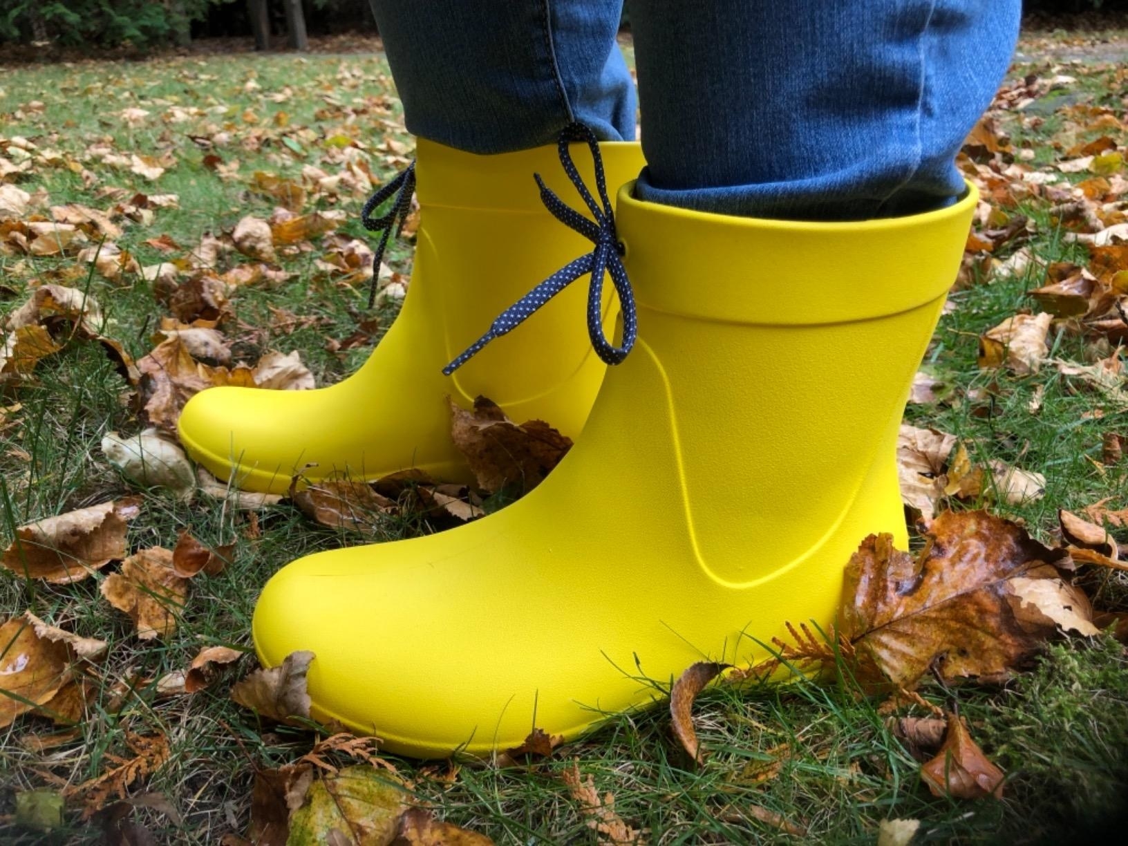 reviewer wearing bright yellow above-the-ankle single-piece boots