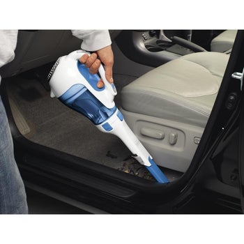 person vacuuming the floor of their car with the cordless vacuum