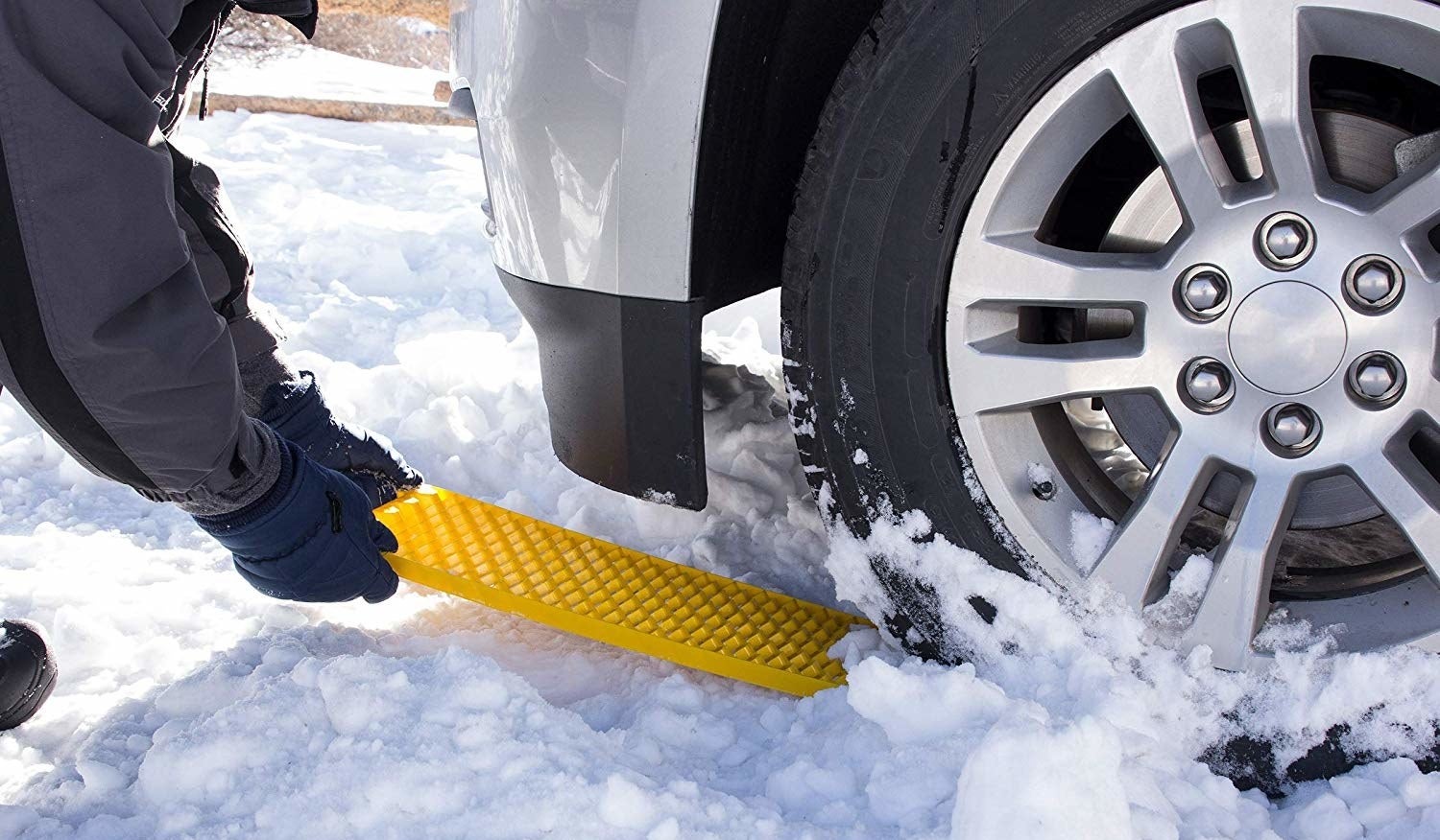 person using the tire traction tool in the snow