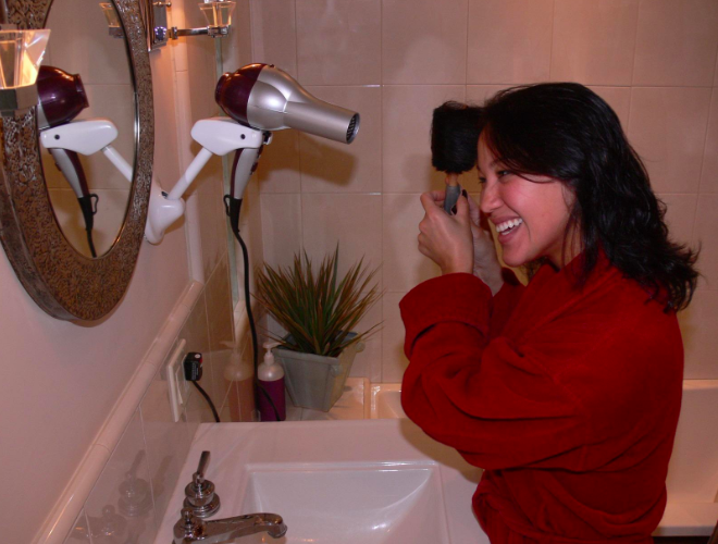 Model styling her hair with mounted dryer holder 