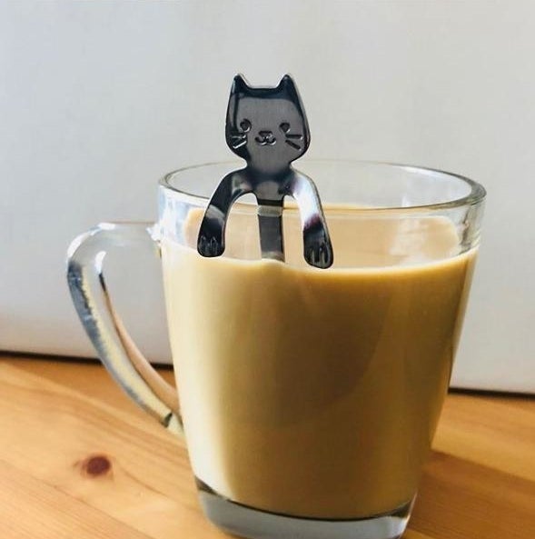 A cup of coffee with the cat teaspoon sticking out of it