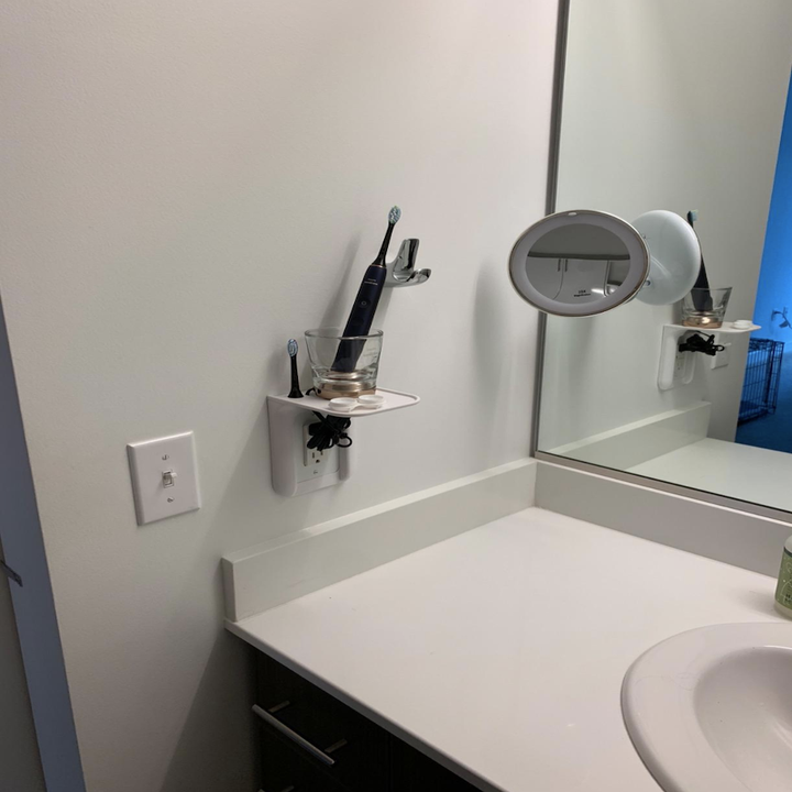 Electric toothbrushes charging on the power perch and plugged into the outlet below