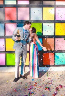 couple standing together in front of colorful wall after opening bottle 