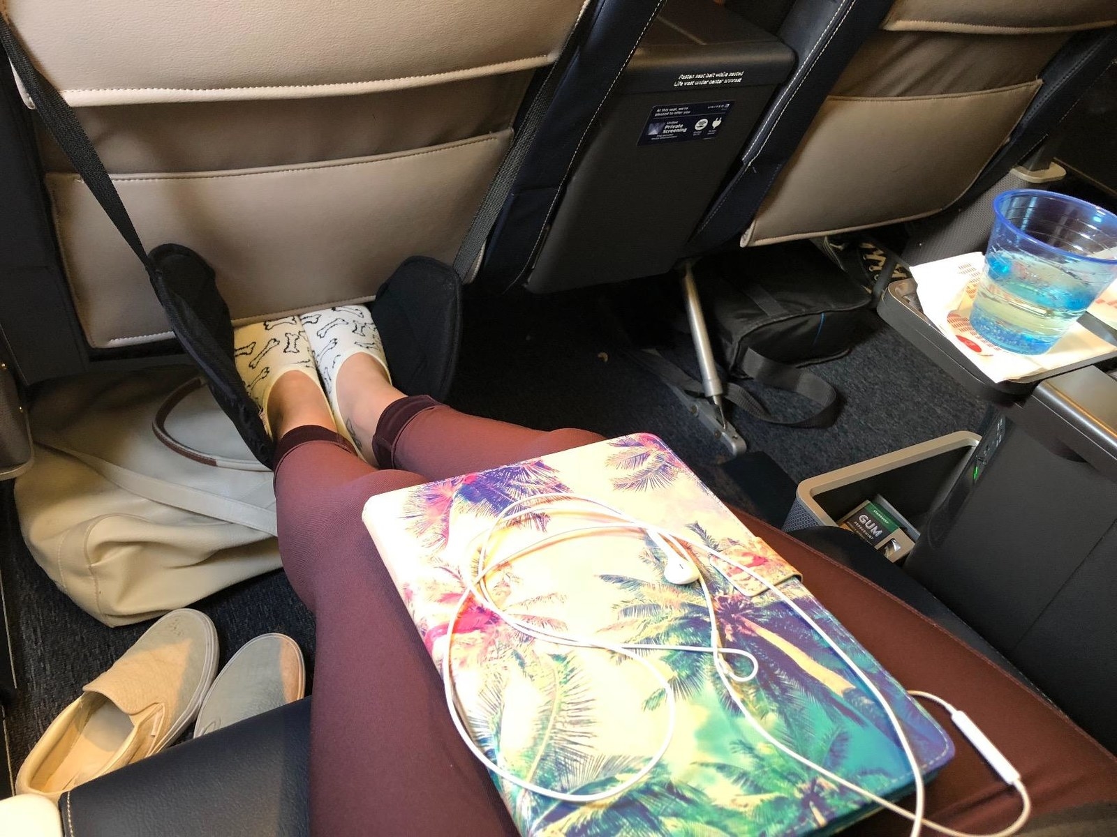 reviewer photo of the black foot hammock on a plane with feet in them