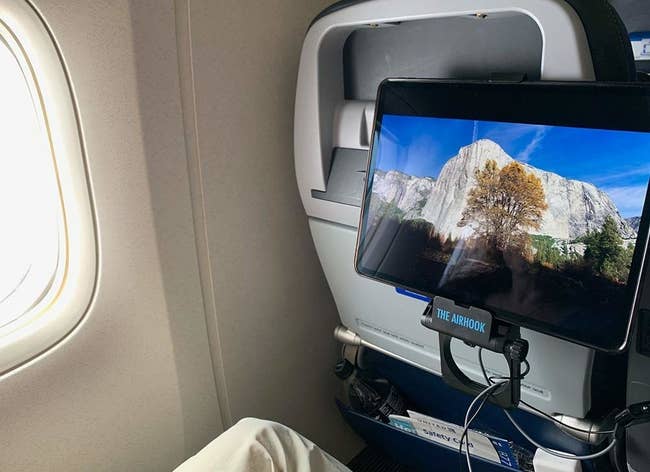 the hook attached to the back of a plane seat with an iPad attached to it