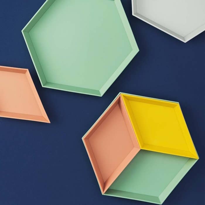 Multi-colored geometric jewelry trays against blue surface 