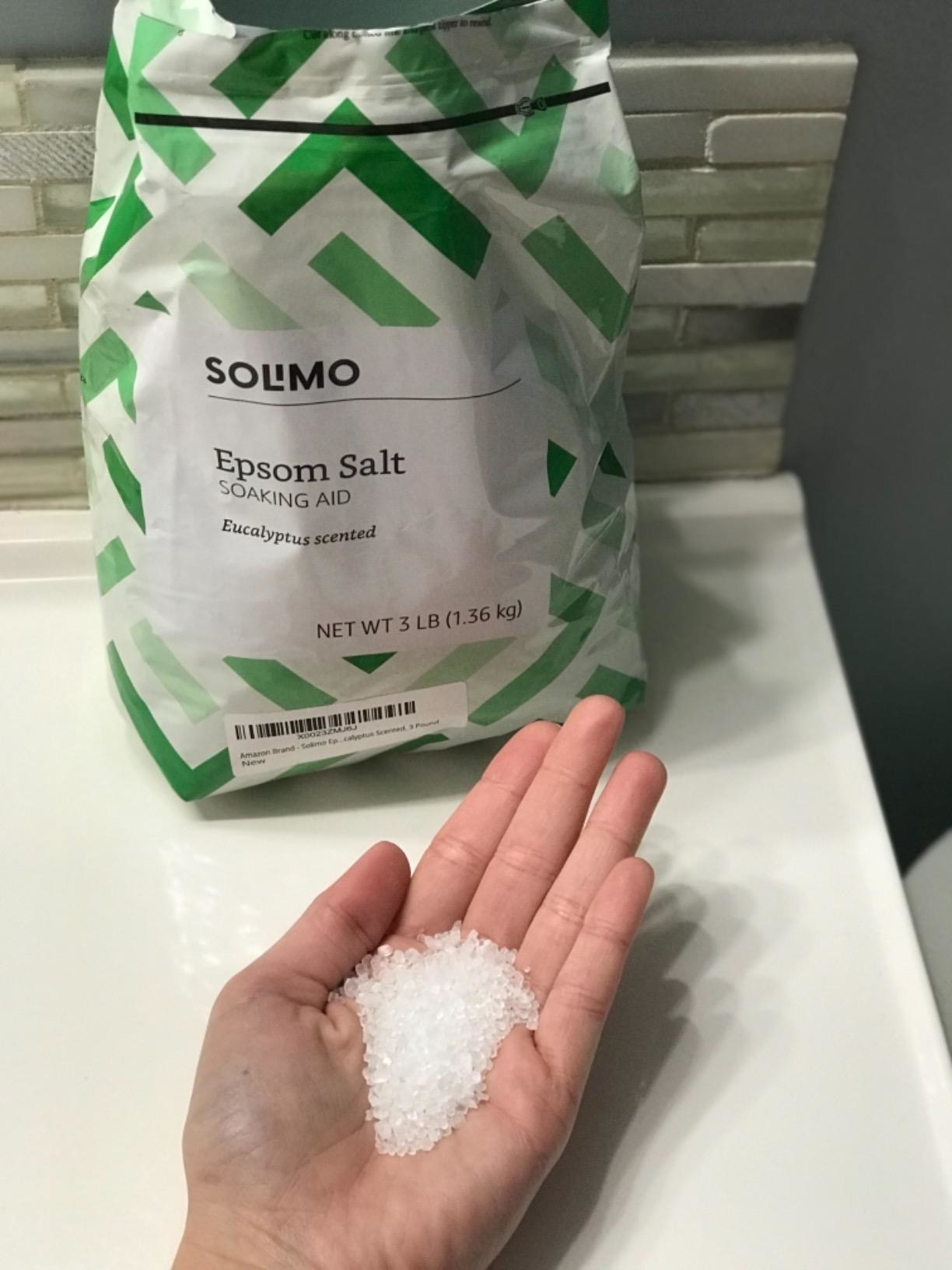 reviewer&#x27;s hand full of the salt next to the bag 