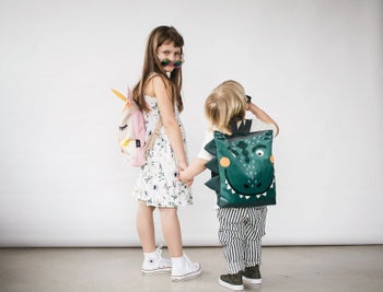 Two children with unicorn and dino backpacks