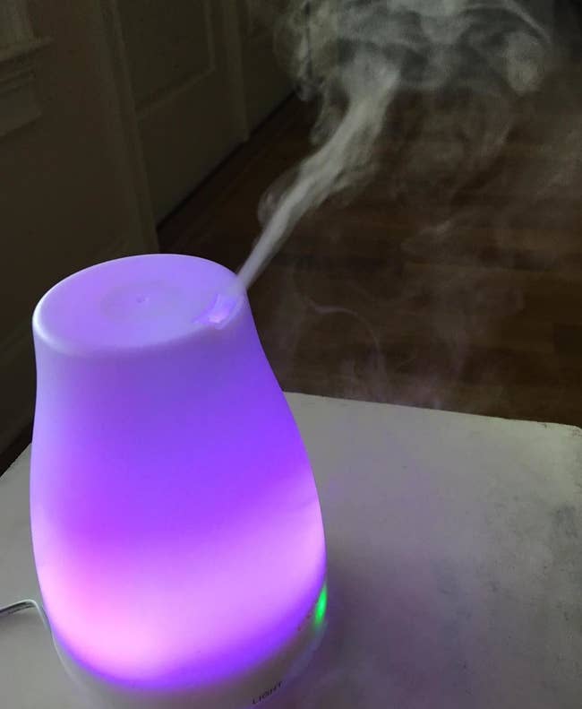 a reviewer's diffuser glowing a purple color and releasing mist