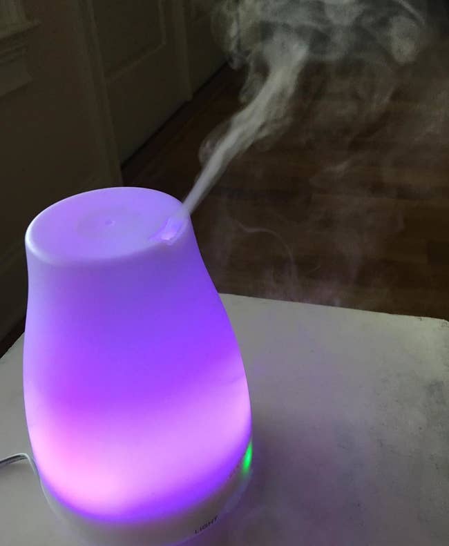 a reviewer's diffuser glowing a purple color and releasing mist
