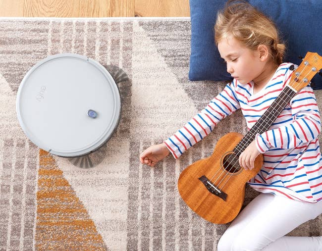The robot vacuum next to a sleeping child