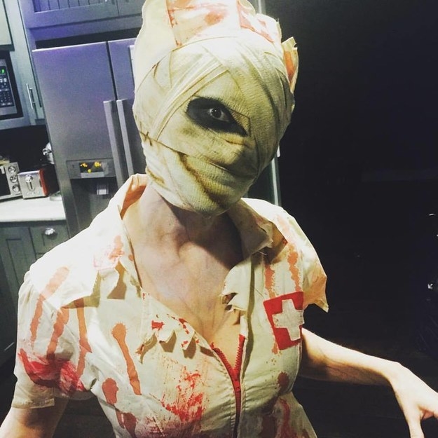 Someone dressed as a bloody nurse with a bandage covering their entire face