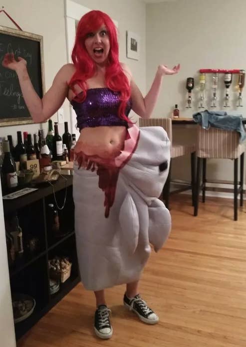 Someone dressed as Ariel from &quot;The Little Mermaid&quot; with fake blood coming out of their side and a stuffed shark attached to them