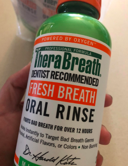 A reviewer showing the bottle of oral rinse