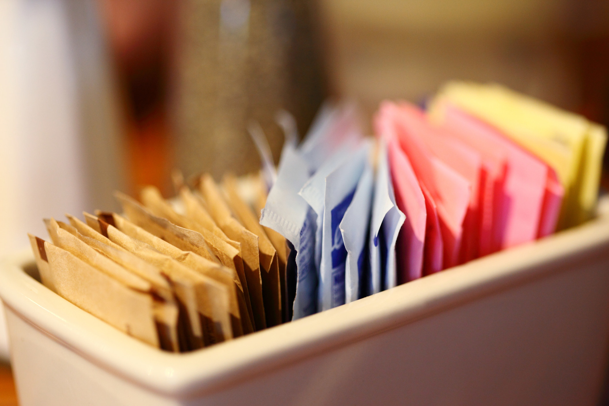 A close up of a dish holding various different sugar packets