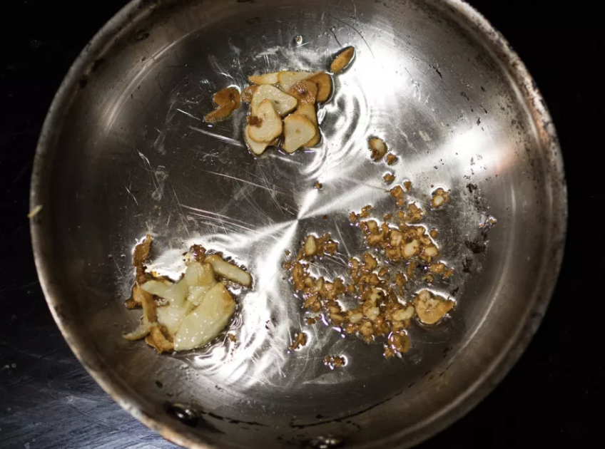 A stovetop pan with burnt garlic in it