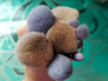 Reviewer holding brushes like a floral bouquet, showing the dark splotches of makeup and gray, brown, and tan bristles 