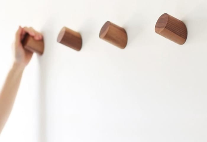 set of four brown wood hooks in a line on a wall