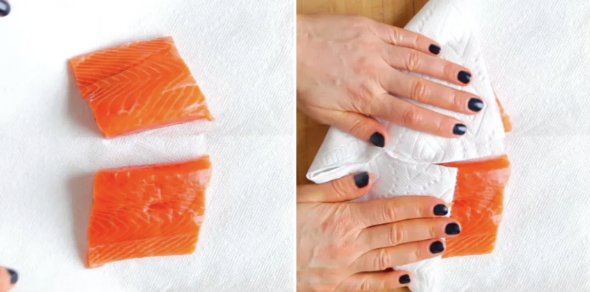 Two salmon fillets being dabbed with a paper towel