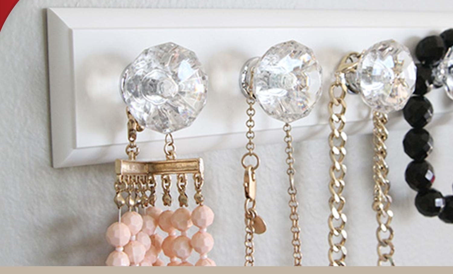 Four necklaces hanging from a rack with four knobs