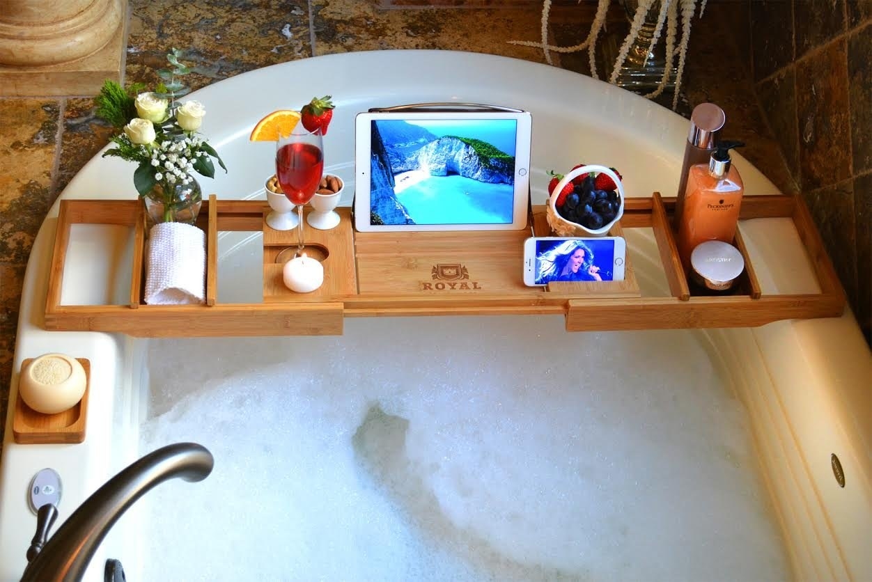 wooden tray over bathtub with ipad, wine, flowers, and scrubs 