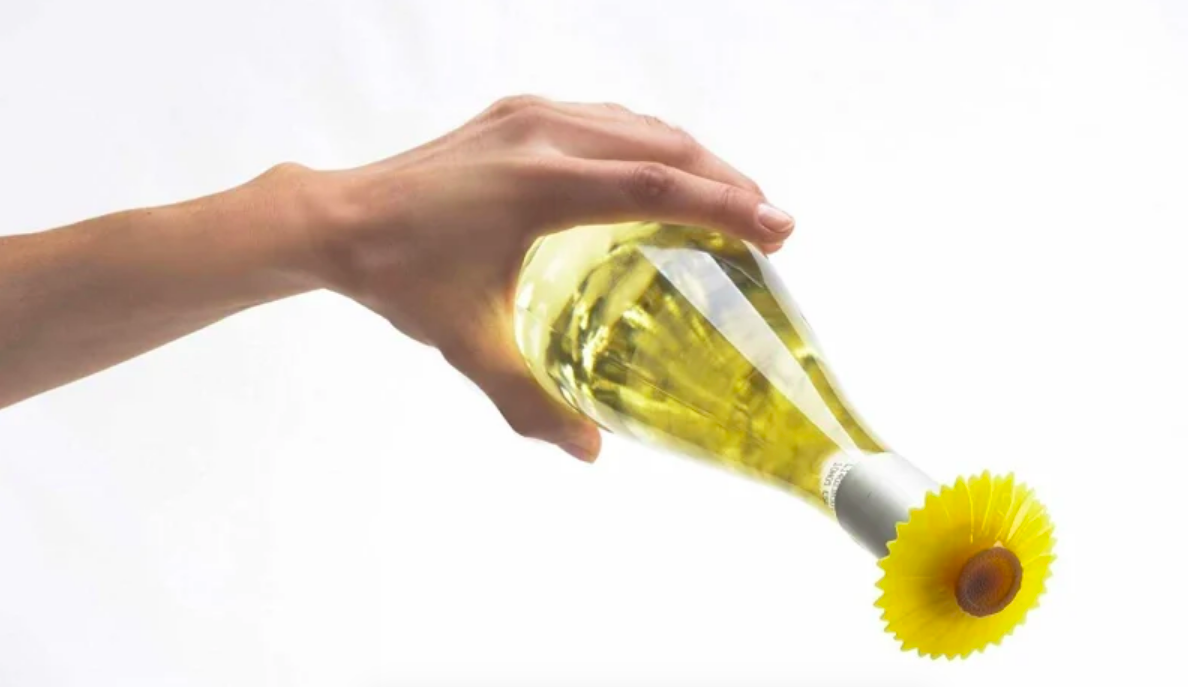 Person tipping wine bottle with floral stopper on top 